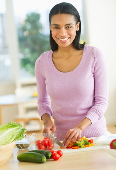 Portrait of woman chopping vegetables in kitchen.