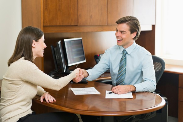 Businessman and client shaking hands in office.