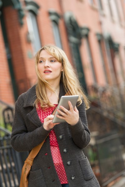 Woman using digital tablet on street.