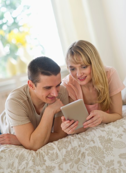 Couple lying on bed and using digital tablet.