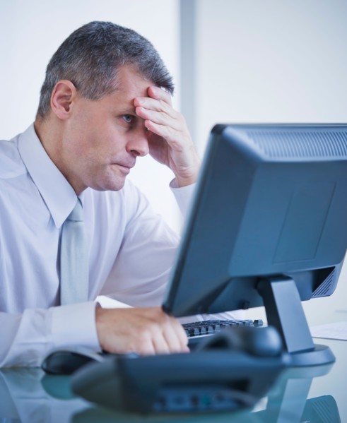 Portrait of worried businessman working at desk. Photo : Daniel Grill