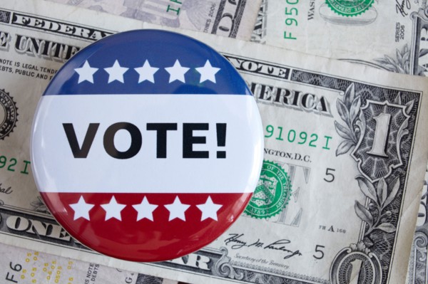 Studio shot of vote pin and one dollar banknotes. Photo : Winslow Productions