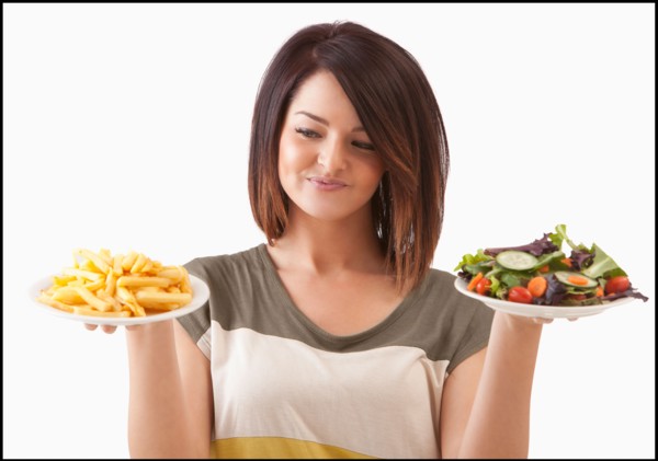 Young woman choosing between healthy and unhealthy food. Photo : Mike Kemp