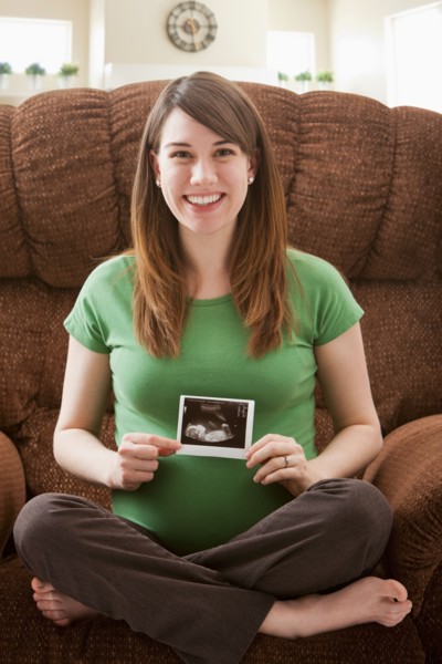 Portrait of pregnant woman showing ultrasonography scan. Photo : Mike Kemp