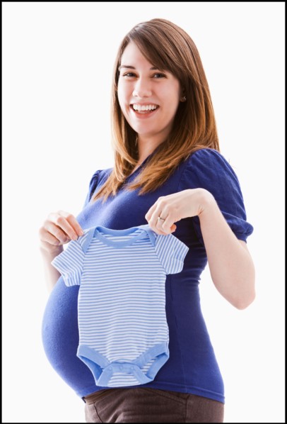 Studio Shot of woman holing baby blue onesie. Photo : Mike Kemp