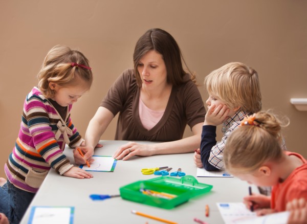 Mid adult woman teaching children (2-3, 4-5) drawing in kindergarten. Photo : Mike Kemp