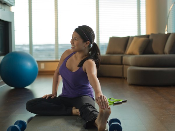 Young woman exercising at home. Photo : Dan Bannister