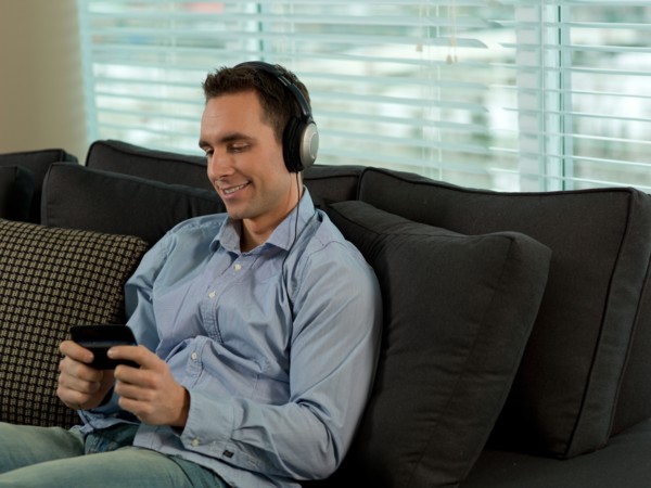 Man sitting on sofa listening music. Photo : Dan Bannister