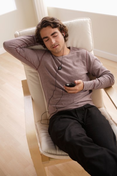 Young man listening music on armchair. Photo : Rob Lewine