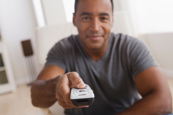 Mature man holding remote control, focus on foreground. Photo : Rob Lewine