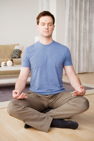 Mid adult man meditating at home. Photo : Rob Lewine