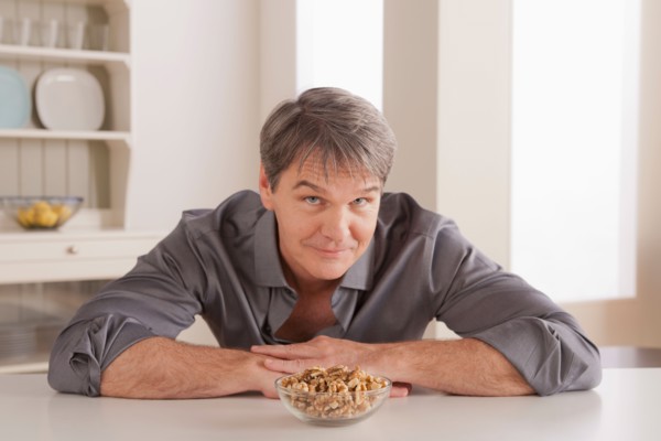 Portrait of mature man with snacks on table. Photo : Rob Lewine