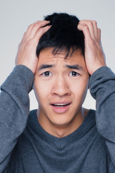 Studio portrait of young man with head in hands. Photo : Rob Lewine
