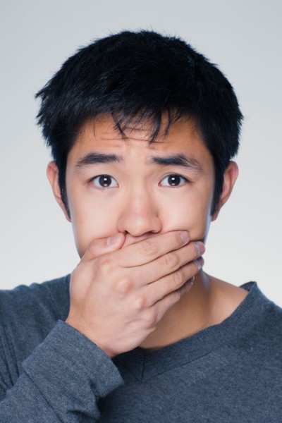 Studio portrait of young man covering mouth. Photo : Rob Lewine