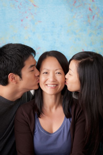 Smiling mother kissed by her children. Photo : Rob Lewine
