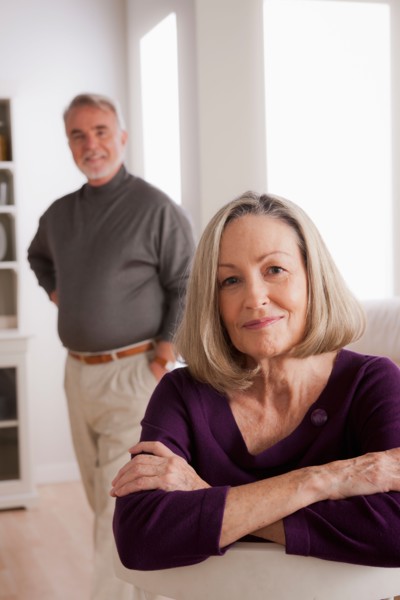 Portrait of smiling senior woman, senior man in background. Photo : Rob Lewine