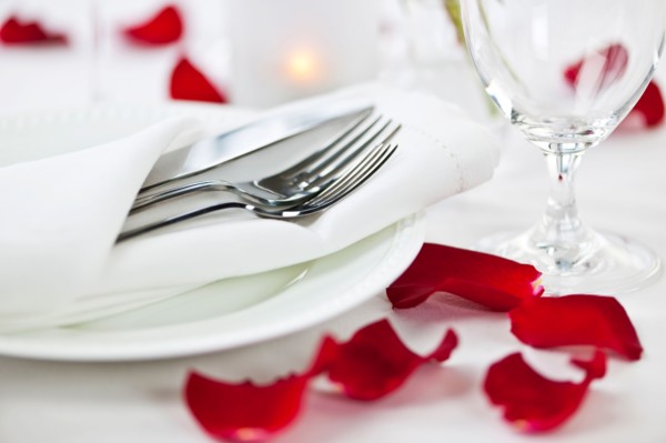 Dishes and cutlery prepared for meal decorated with red roses. Photo : Elena Elisseeva