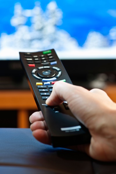 Human hand holding remote control . Photo : Elena Elisseeva
