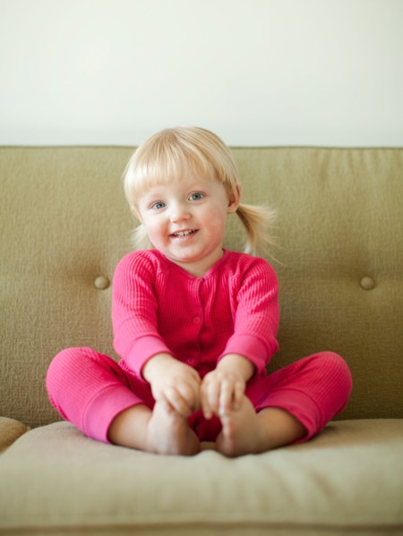 Portrait of baby girl (18-23 months) sitting on sofa. Photo : Jessica Peterson