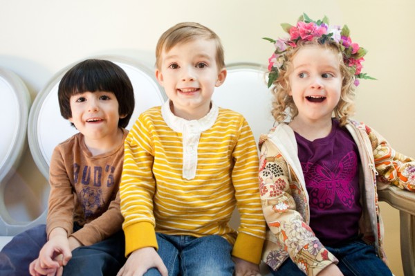 Studio Shot portrait of three children (4-5, 6-7) sitting side by side. Photo : Jessica Peterson