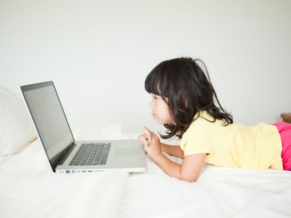Girl lying down in bed, using laptop (4-5). Photo : Jessica Peterson