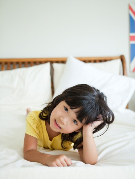 Portrait of girl lying down in bed (4-5). Photo : Jessica Peterson