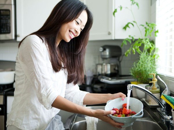 Portrait of young woman washing strawberries. Photo : Jessica Peterson