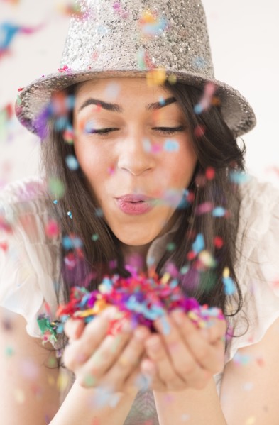 Portrait of young woman blowing confetti.