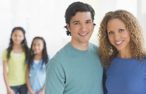 Portrait of parents with daughters (10-13) in background.
