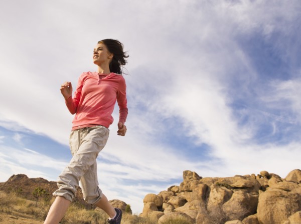 USA, California, Joshua Tree National Park, Young woman jogging in desert.
