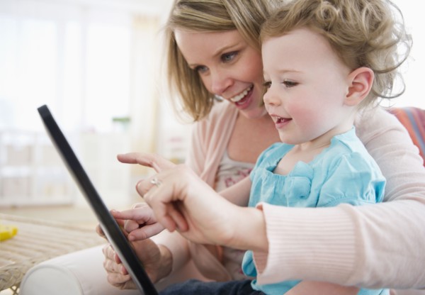 Mother with daughter (-11 months) using digital tablet at home. 
Photo : Jamie Grill