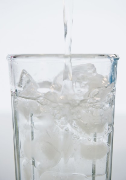 Water being poured into glass with ice cubes. 
Photo : Jamie Grill