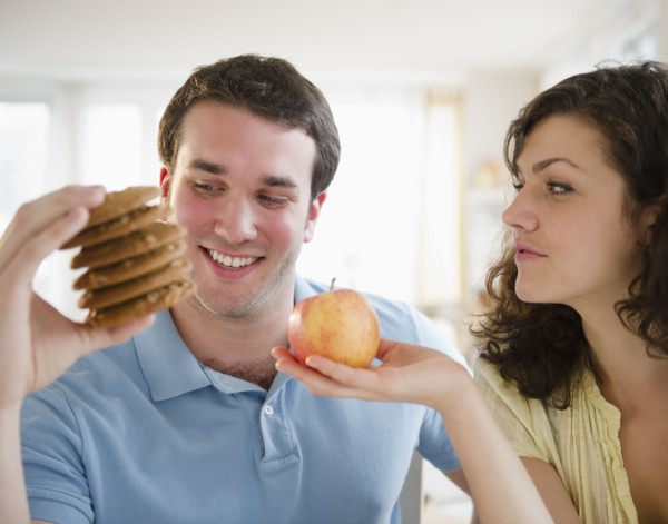 Couple holding cookies and apple. 
Photo : Jamie Grill