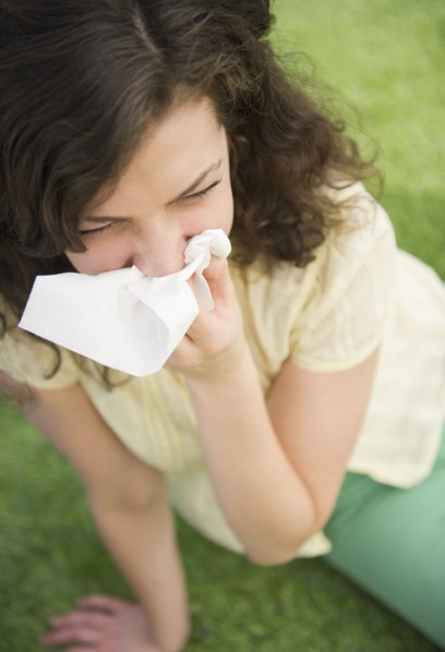 Woman blowing nose while sitting on lawn. 
Photo: Jamie Grill