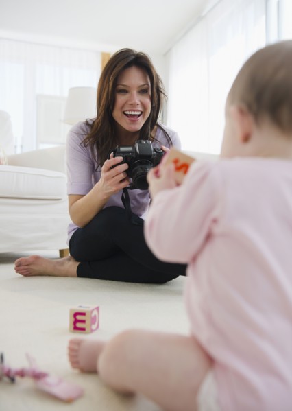 Mother photographing baby daughter (6-11 months). 
Photo : Jamie Grill