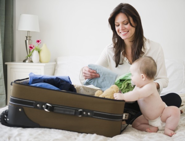 Mother with baby daughter (6-11 months) packing suitcase. 
Photo : Jamie Grill