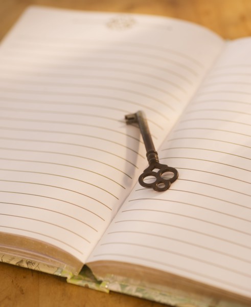 Close up of open notebook with key, studio shot. 
Photo : Daniel Grill