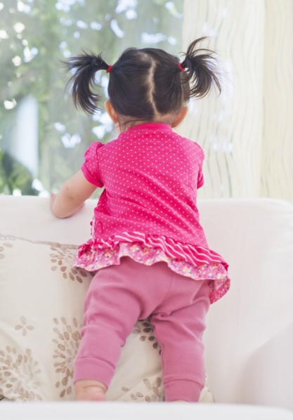 Baby girl (12-17 months) looking through window. 
Photo : Daniel Grill