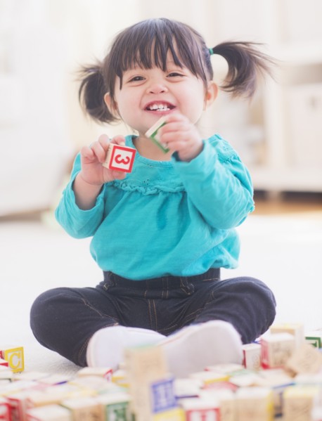 Portrait of baby girl (12-17 months) playing alphabet blocks. 
Photo: Daniel Grill