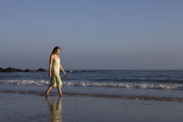 France, Pas-de-Calais, Escalles, Young woman strolling on empty beach. 
Photo : Jan Scherders