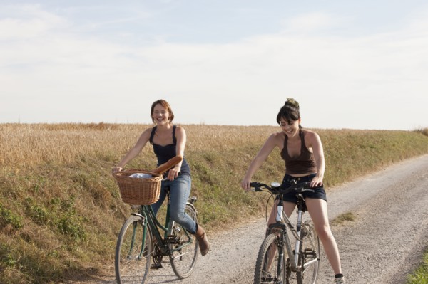 France, Picardie, Albert, Young women on bikes on country road. 
Photo: Jan Scherders
