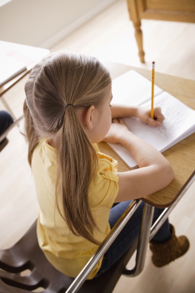 Schoolgirl focused on writing in classroom. 
Photo : Rob Lewine