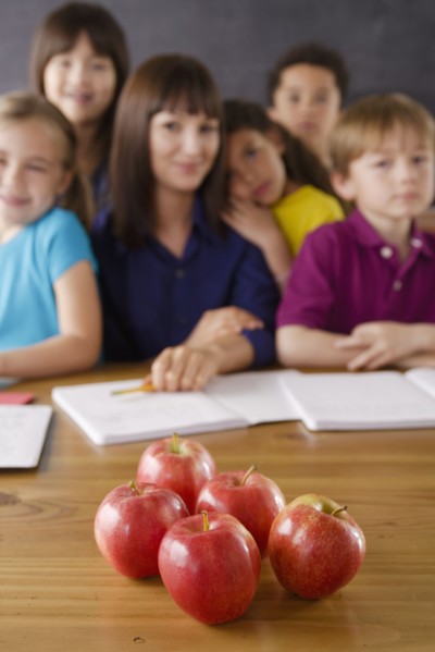 Teacher with group of pupils and apples on desk. 
Photo : Rob Lewine