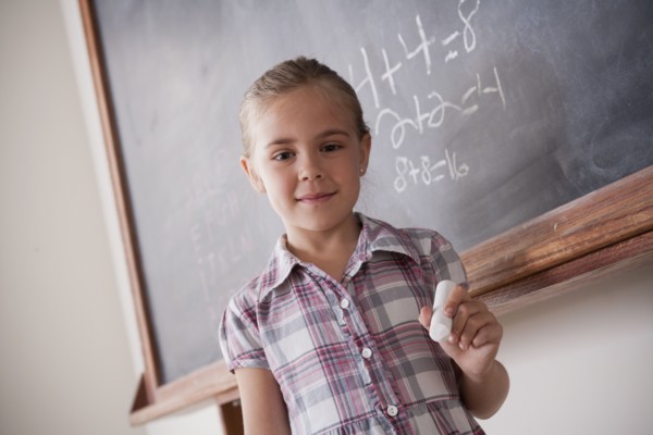 Portrait of schoolgirl holding chalk. 
Photo: Rob Lewine