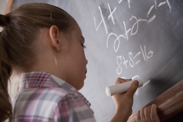 Schoolgirl writing on blackboard. 
Photo: Rob Lewine