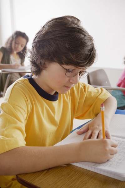 Portrait of schoolboy (10-11) writing. 
Photo : Rob Lewine