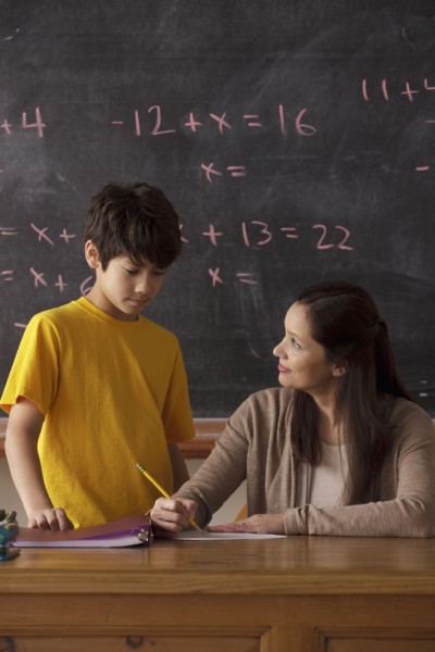 Schoolboy (12-13) and teacher with blackboard in background. 
Photo: Rob Lewine