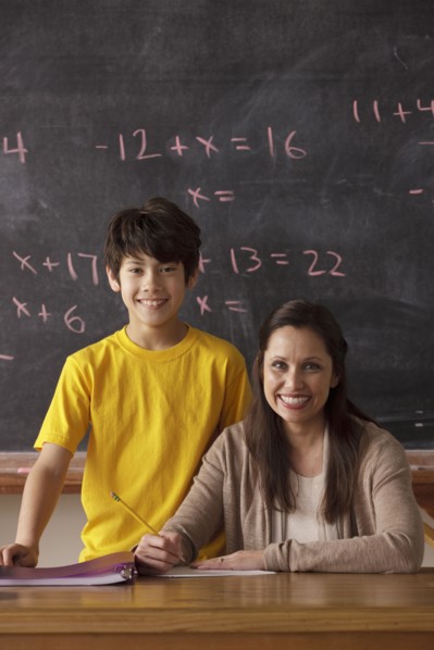 Portrait of schoolboy (12-13) and teacher with blackboard in background. 
Photo: Rob Lewine