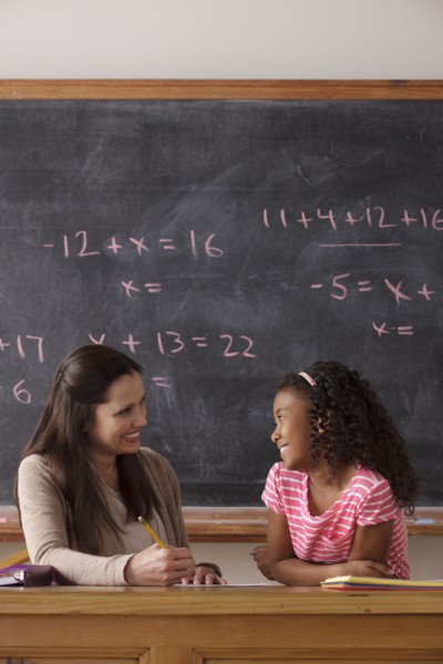 Schoolgirl (10-11) and teacher face to face with blackboard in background. 
Photo : Rob Lewine