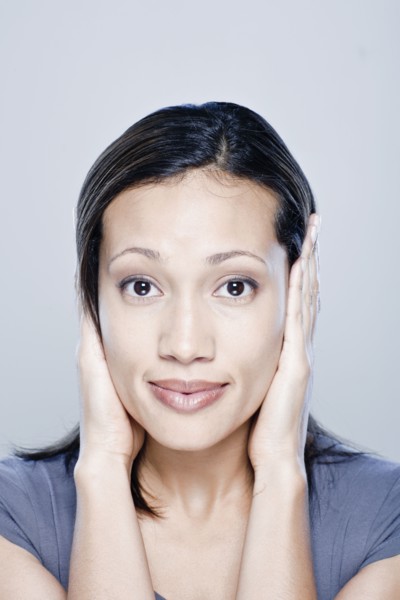 Portrait of young woman with hands covering ears, studio shot. 
Photo : Rob Lewine
